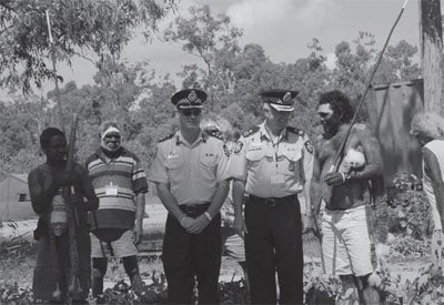 A photo of 2 policeman along side with some Indigenous people