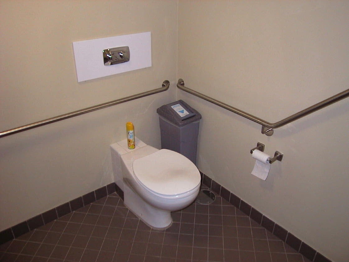 Accessible toilet: good circulation space, handrail correctly placed to lead downwards towards pan