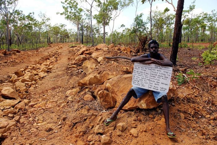 Intervention by Belinda Mason. Indigenous man holding sign on a road in the bush